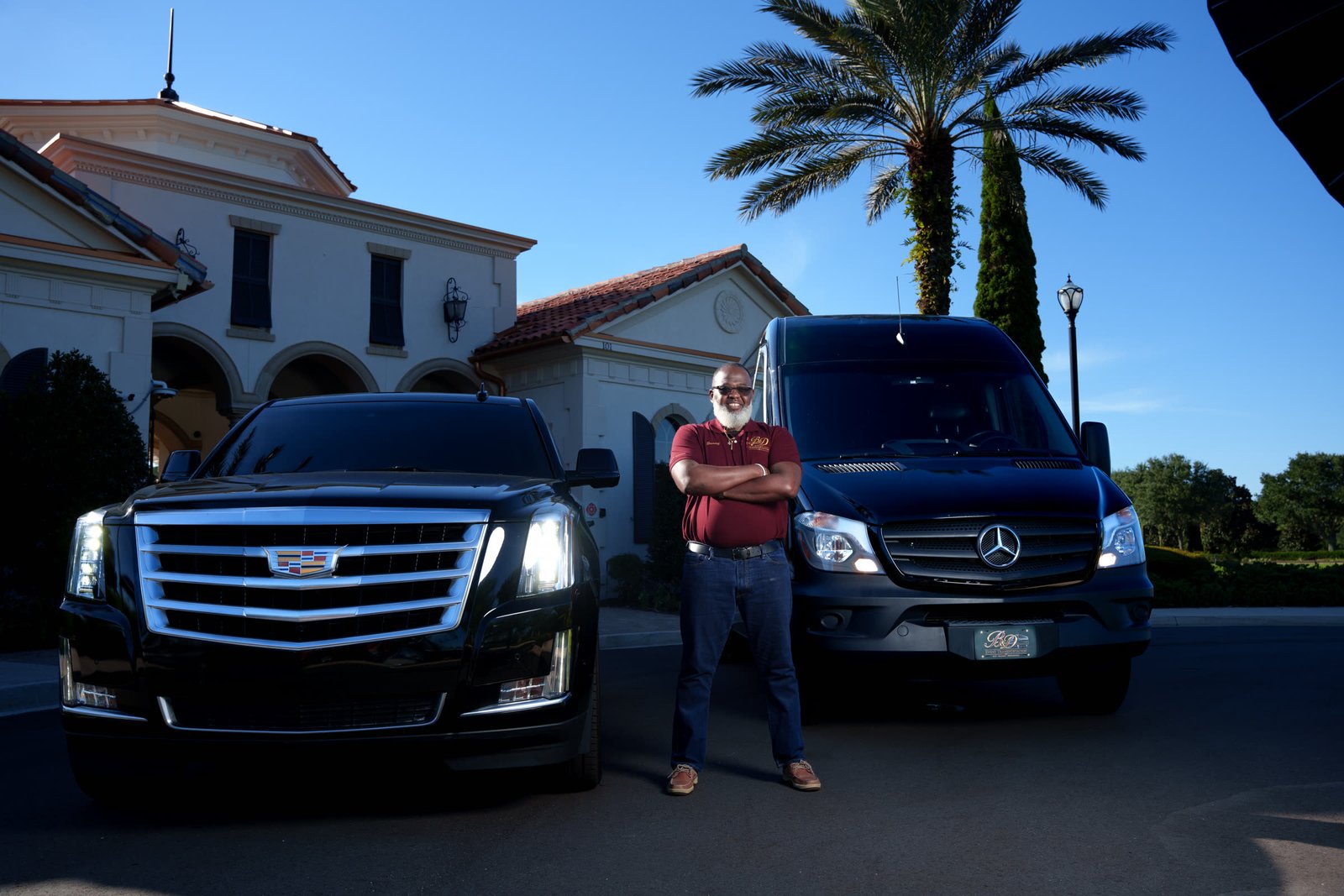 Danny standing between the Cadillac Escalade and Mercedes-Benz Sprinter